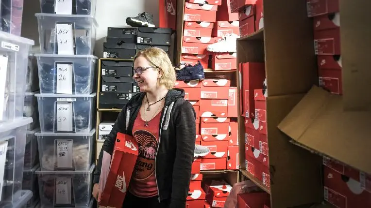 A shop owner standing among inventory and shipping boxes